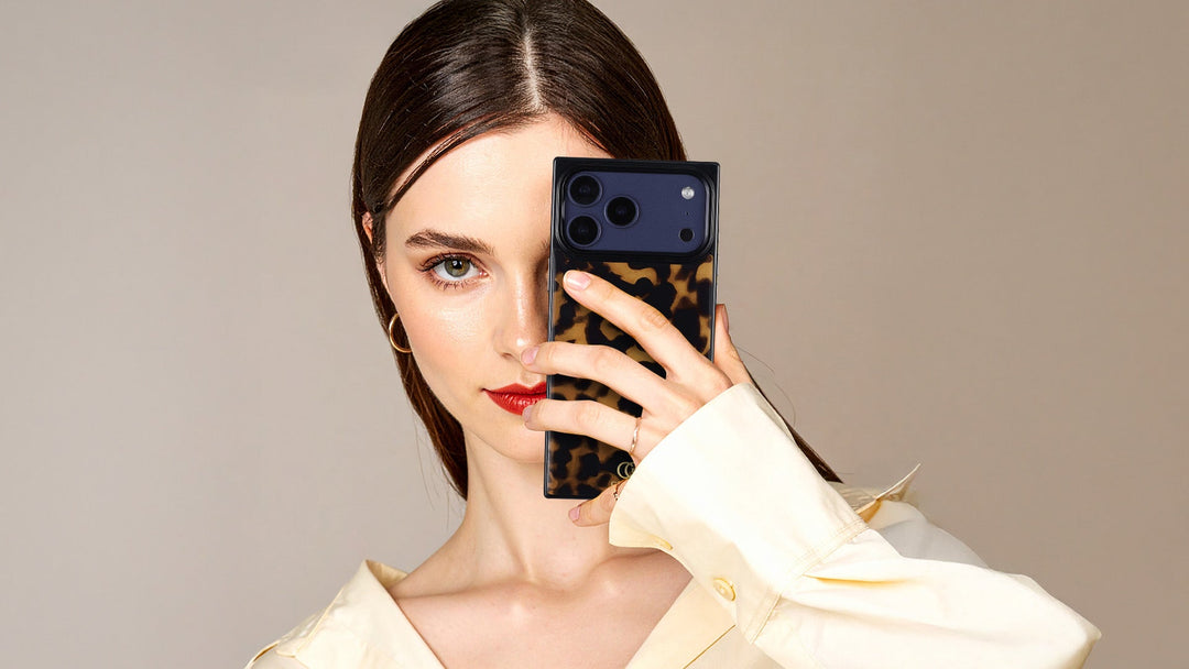 A woman holding a leopard print rectangle iPhone case over half her face