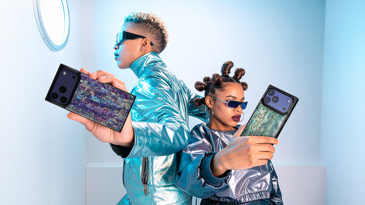 Two models in metallic jackets holding phone cases with a dark abalone shell pattern