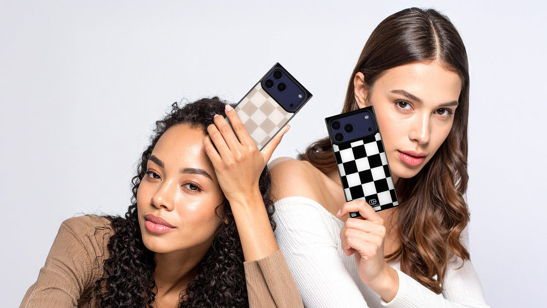Two women each holding an iPhone case with a checkerboard pattern, one tan and cream, one black and white