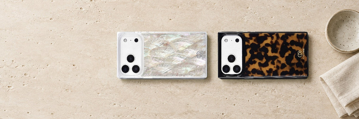 COCOMII Real Mother of Pearl and Tortoiseshell rectangle cases lying side by side on a pale travertine surface beside a small ceramic dish and a linen napkin
