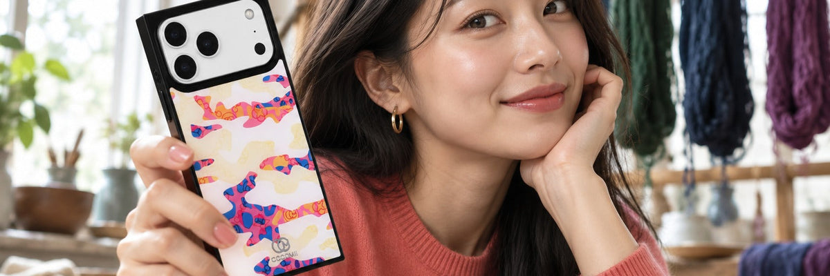 Woman in a coral cashmere knit in a dye studio looking round with a COCOMII leopard print case in Princely Paisley