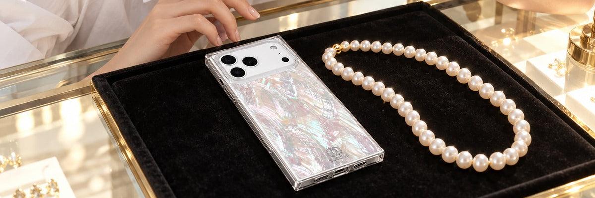 Woman in a white shirt dress at a jeweler's counter looking at pearls with a COCOMII Mother of Pearl case in Natural