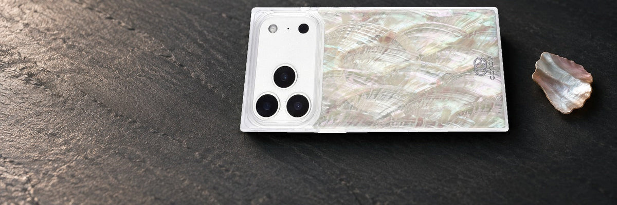 COCOMII Real Mother of Pearl rectangle case lying flat on dark slate beside a small loose shell fragment