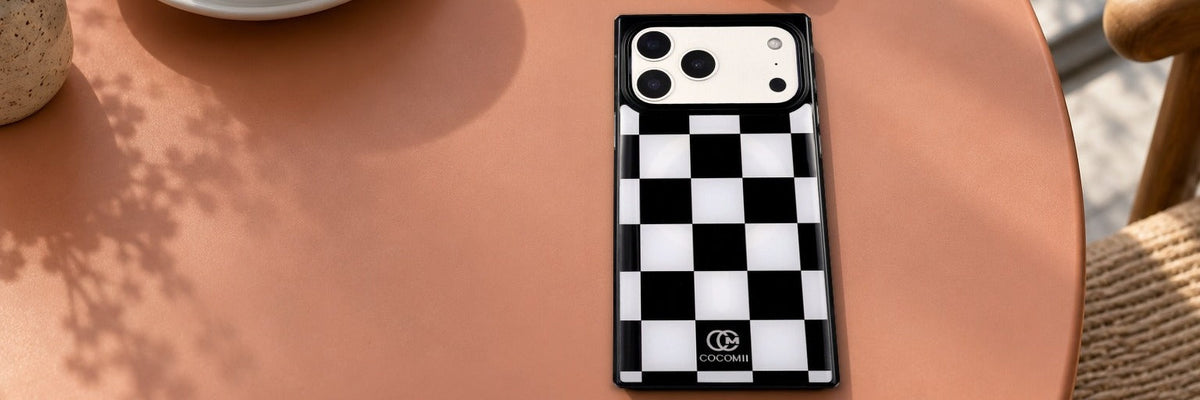 COCOMII checkered case in Monochrome on a terracotta cafe table beside a cappuccino