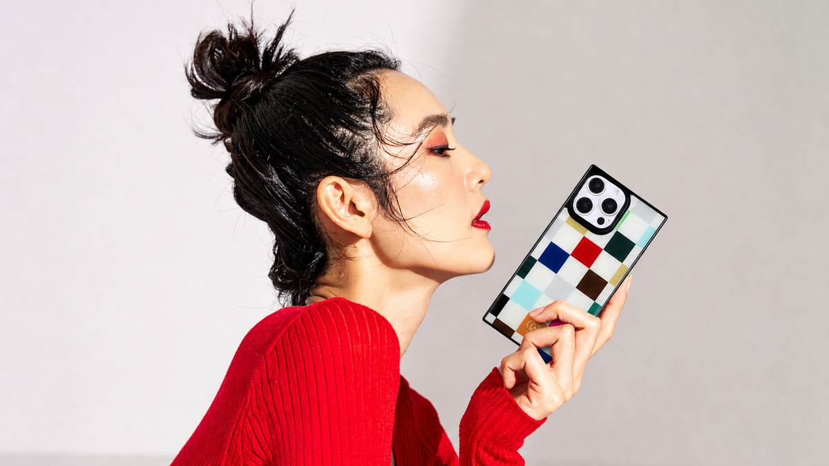 Woman in a red sweater holding a COCOMII rectangle iPhone case with a colorful checkered pattern